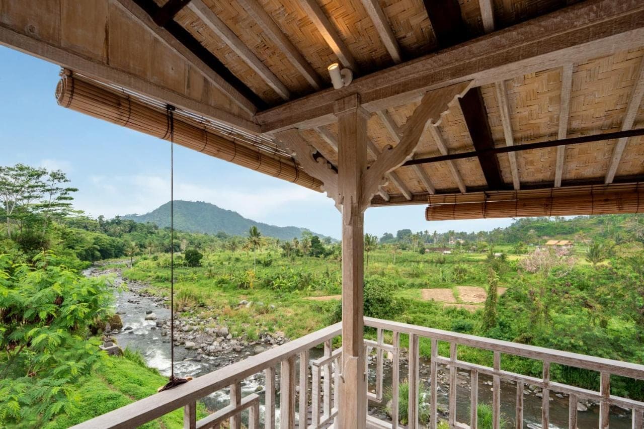 a balcony with a view of a river and mountains at ArtVilla Sidemen River in Sidemen