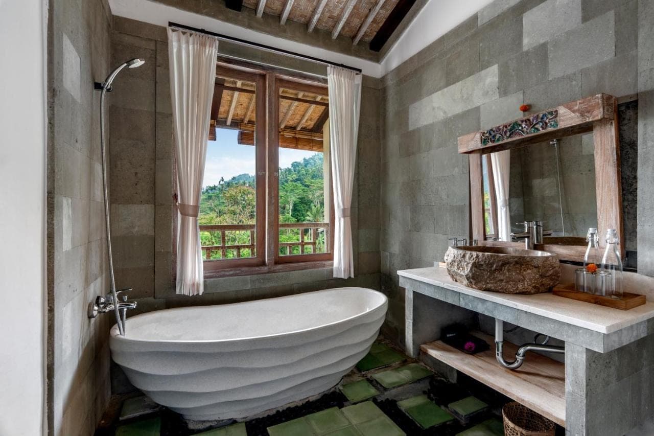 a bathroom with a large tub and a window at ArtVilla Sidemen River in Sidemen