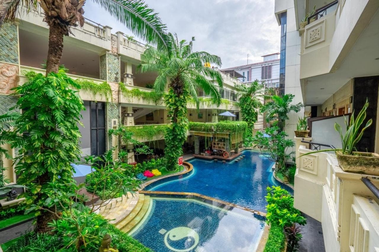 an apartment with a swimming pool in a building at Famous Hotel Kuta Formerly Permata Kuta Hotel in Kuta