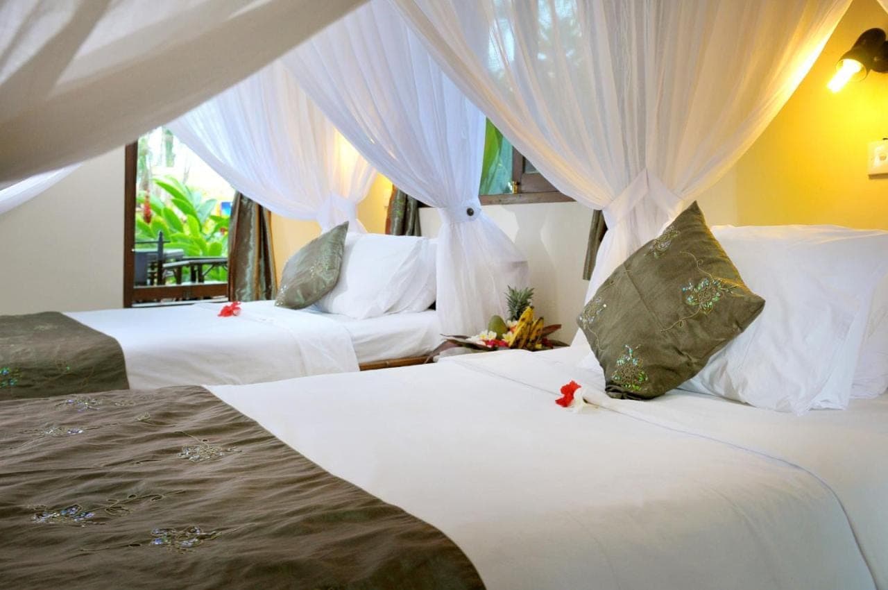 a bedroom with two beds with white sheets and curtains at Coral View Villas in Amed