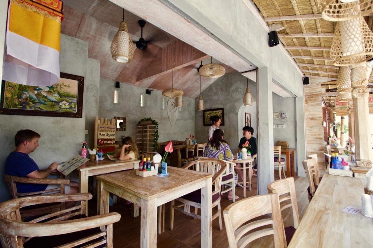 a group of people sitting at tables in a restaurant at Pacha House in Ubud