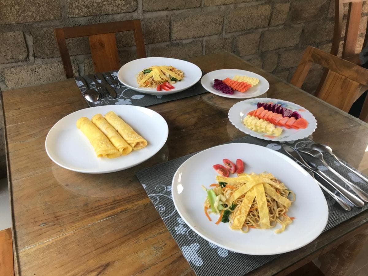 a wooden table with plates of food on it at Pacha House in Ubud