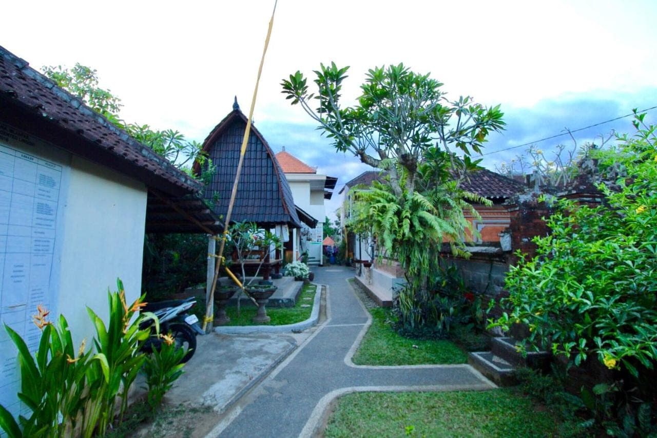 a walkway through a garden with houses and trees at Pacha House in Ubud