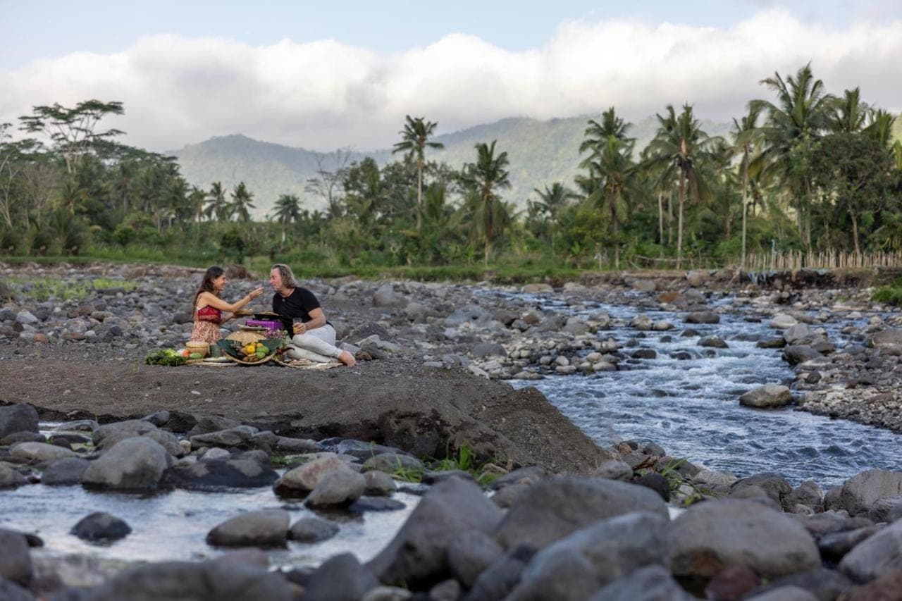 two women sitting on a rock by a river at Natya River Sidemen in Sidemen