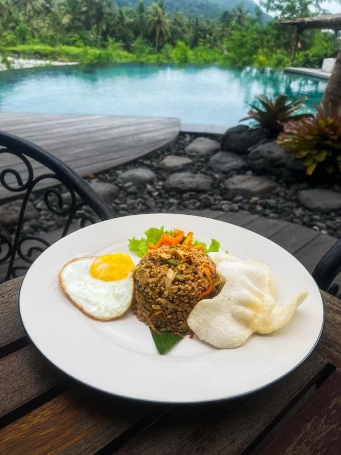 a plate of food with an egg on a table at Natya River Sidemen in Sidemen