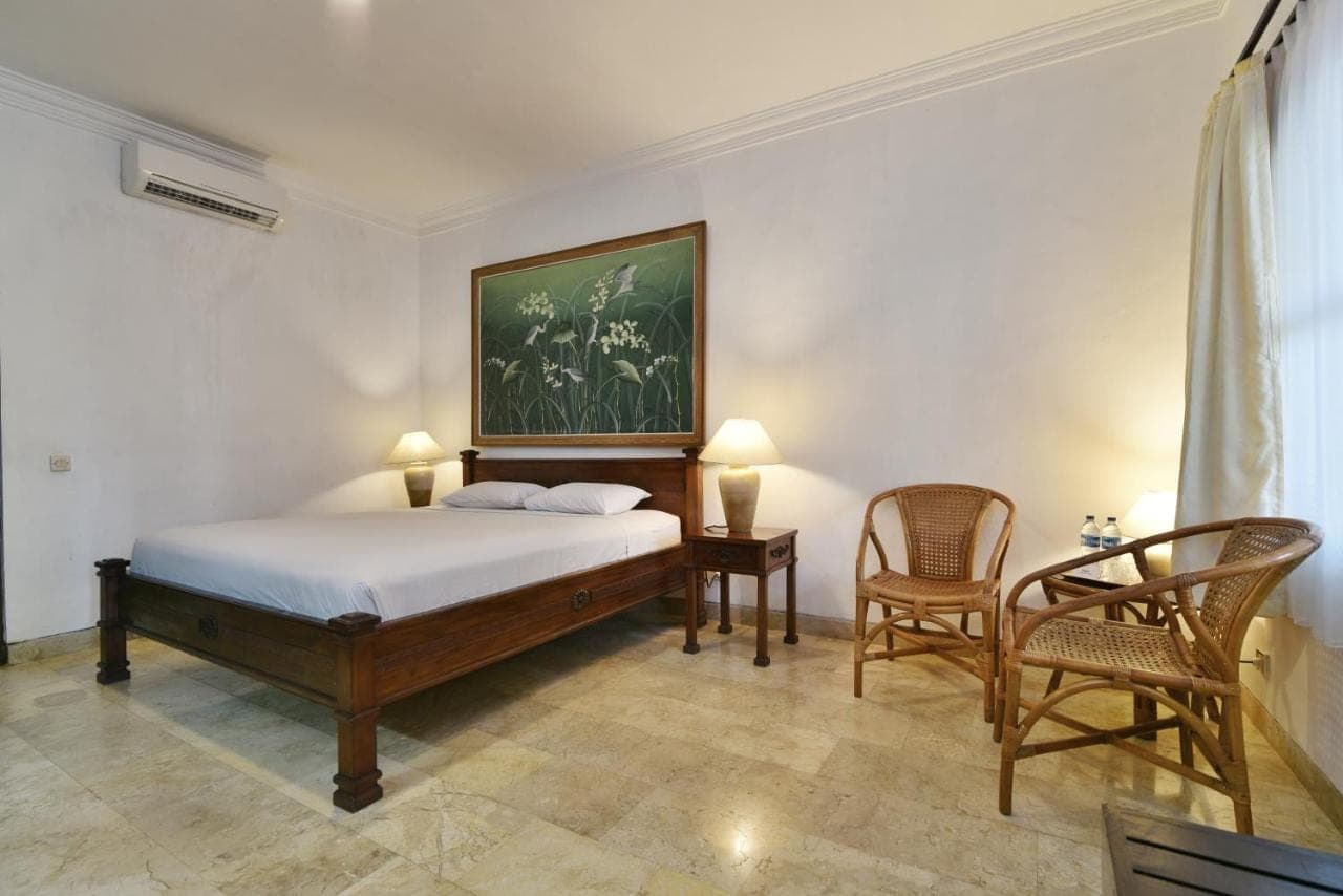 a bedroom with a bed with a painting on the wall at Palm Garden Hotel in Sanur