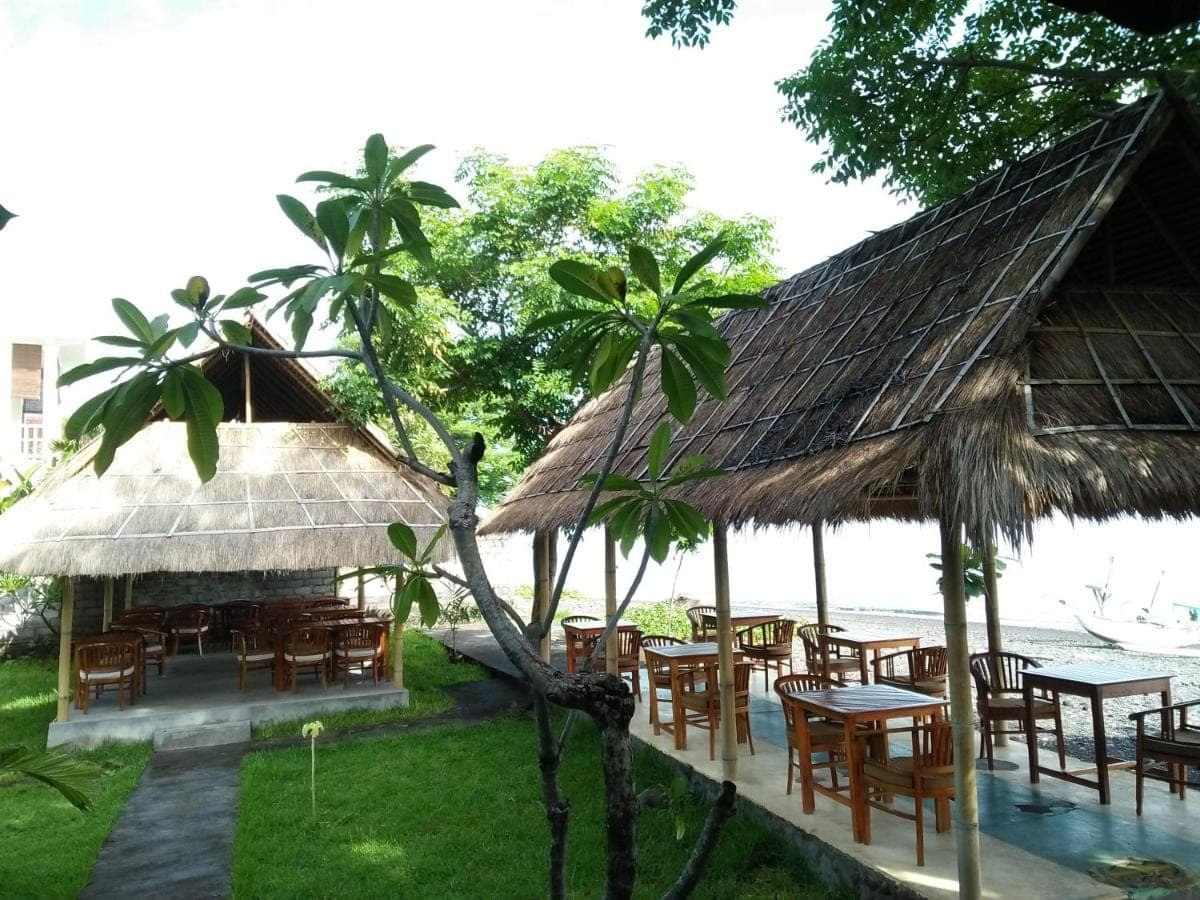 a restaurant with tables and chairs next to the water at Bamboo Bali in Amed