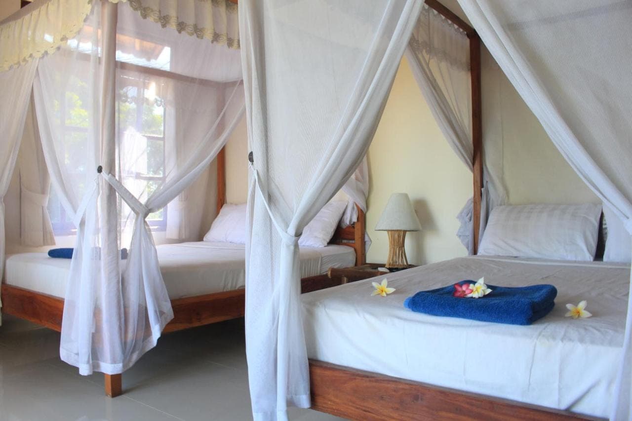 two beds with drapes in a bedroom at Bamboo Bali in Amed