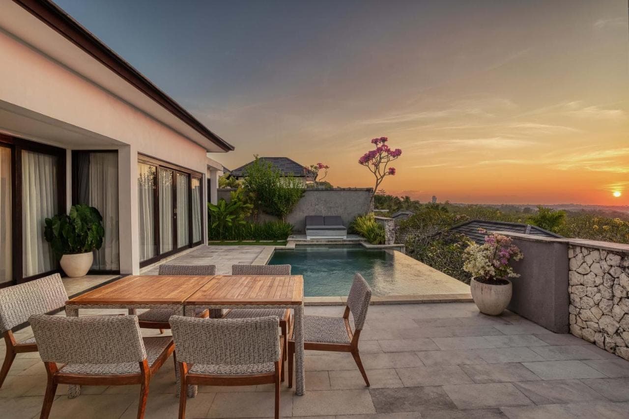 a patio with a table and chairs and a swimming pool at Prasana Villas Uluwatu in Uluwatu