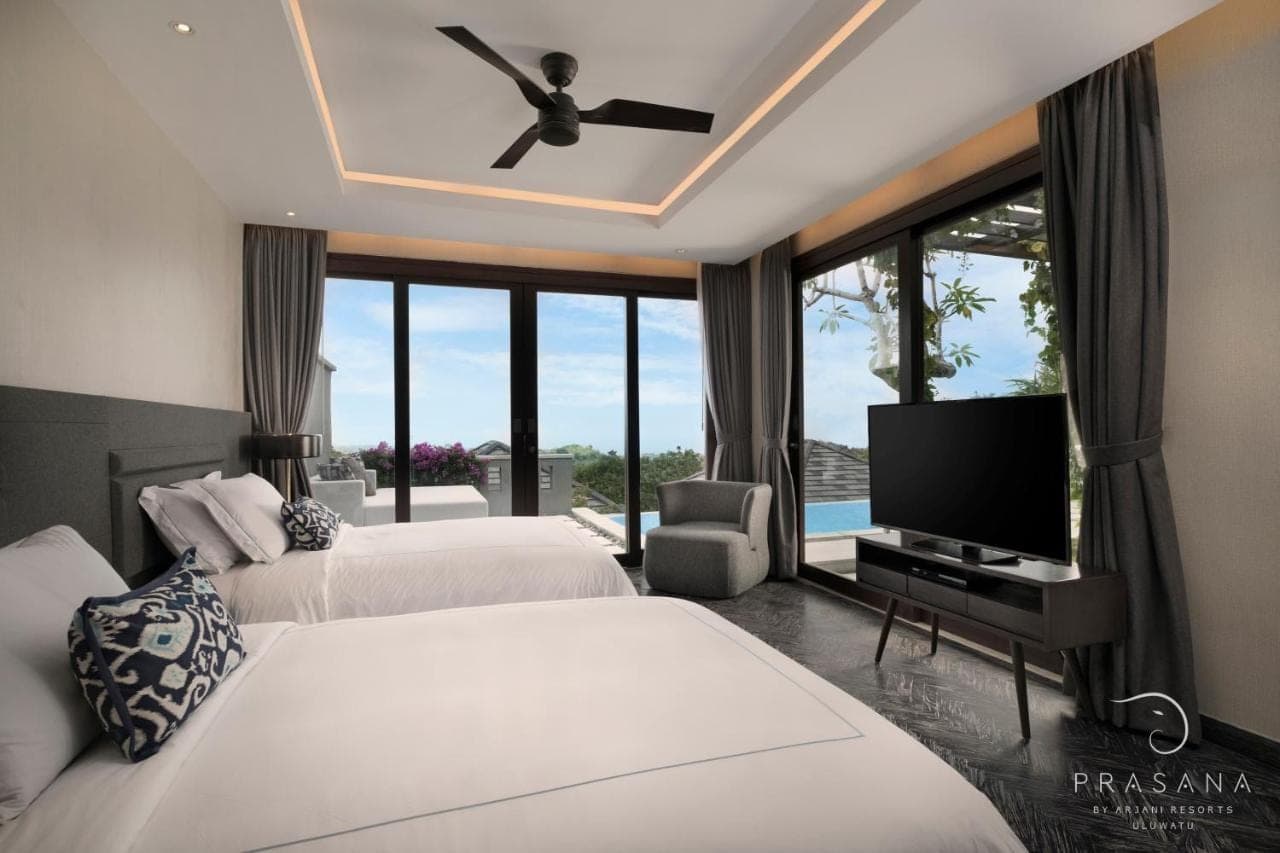 a bedroom with two beds and a flat screen tv at Prasana Villas Uluwatu in Uluwatu