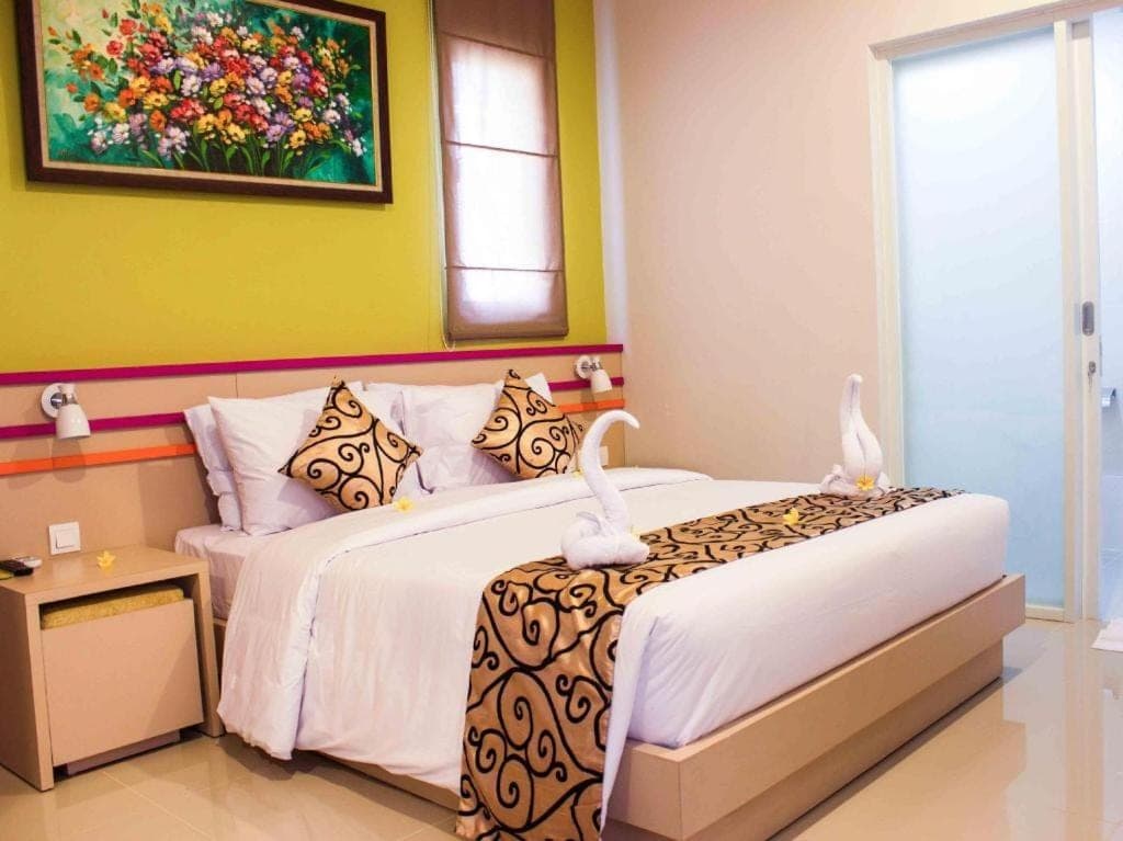 a bedroom with two beds and a painting on the wall at Kemuning Kuta Hotel in Kuta