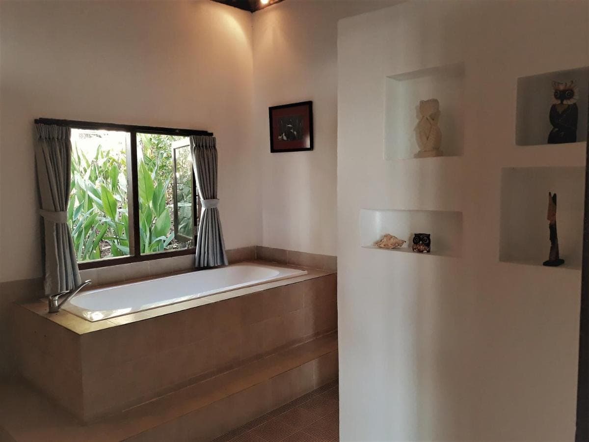 a bath tub in a room with a window at Anda Amed Villas &amp; Spa in Amed