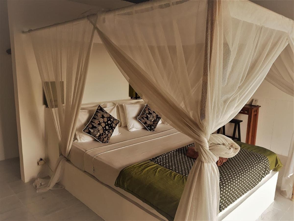 a bedroom with a canopy bed with curtains at Anda Amed Villas &amp; Spa in Amed