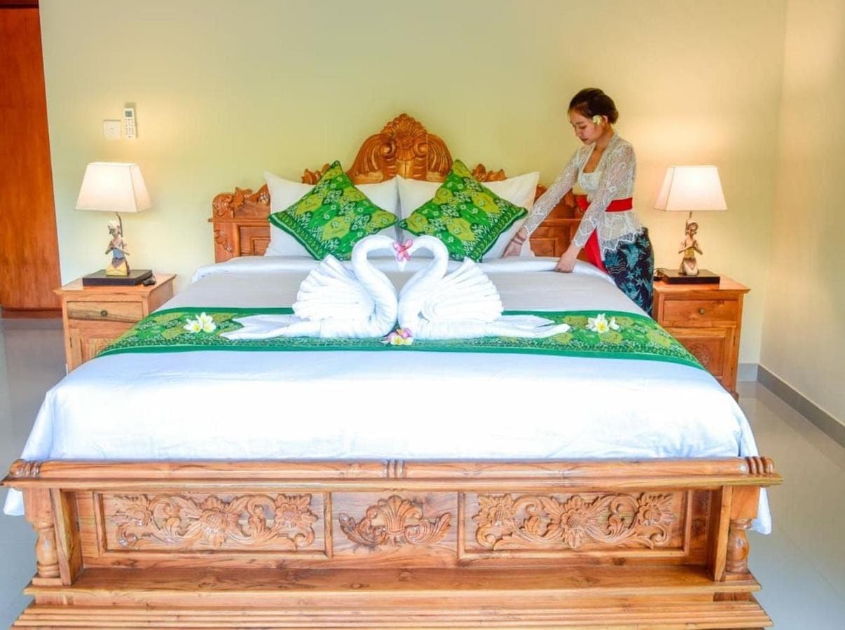 a woman standing next to a bed with two swans on it at Sukun Babonsay Villas in Amed