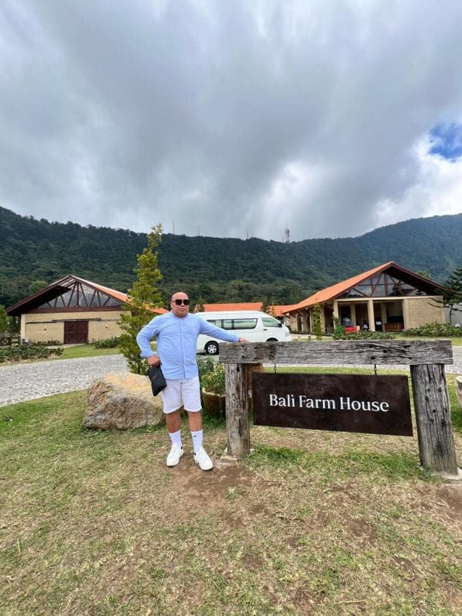 a man standing next to a sign at a ball farm house at James Guest House in Seminyak