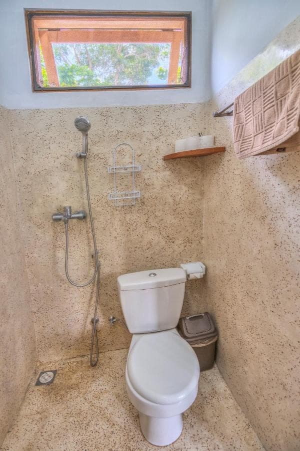 a bathroom with a toilet and a shower at Villa iris Homestay in Uluwatu