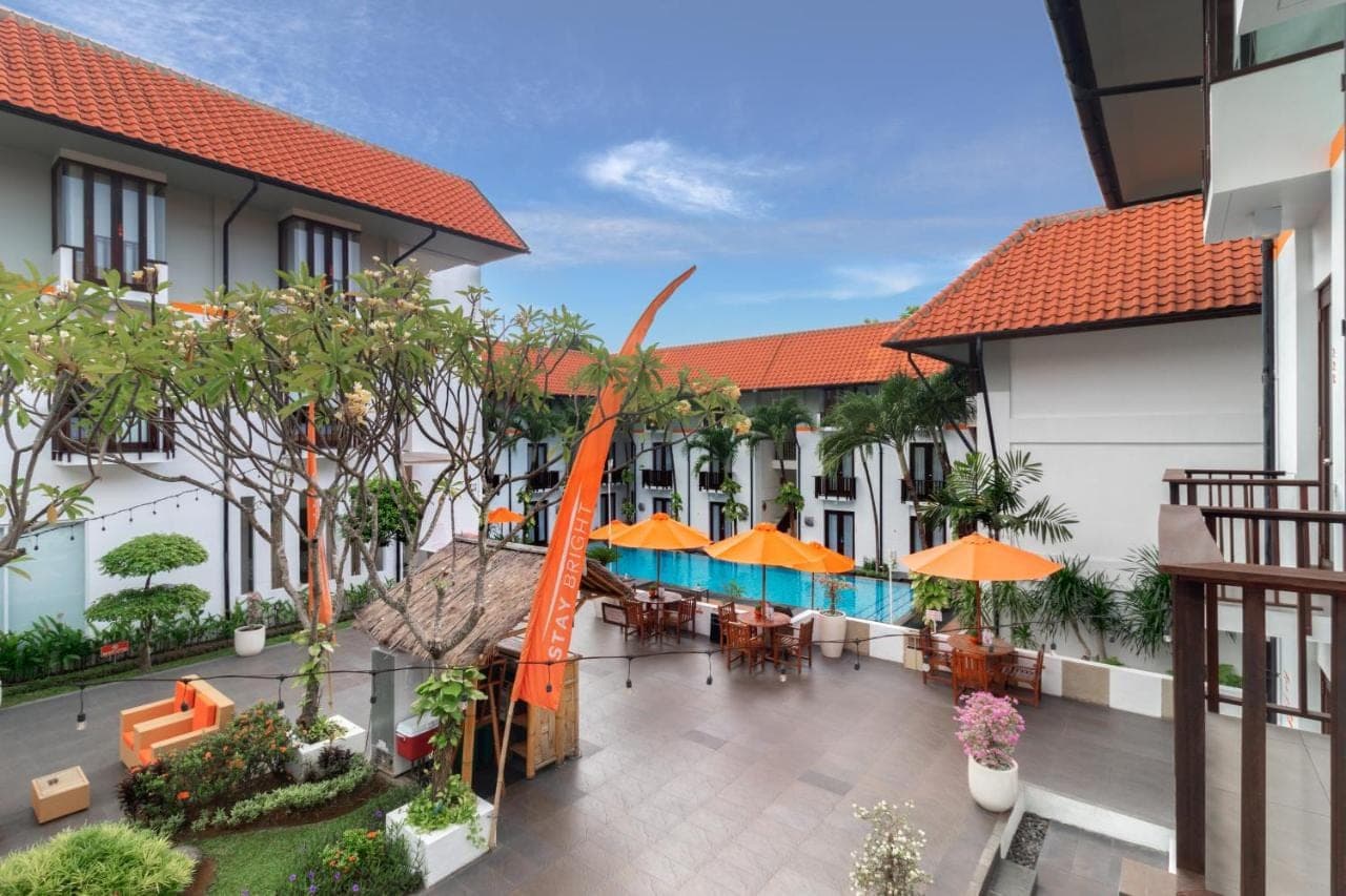 an outdoor courtyard with tables and chairs and umbrellas at HARRIS Hotel Kuta Tuban Bali in Kuta