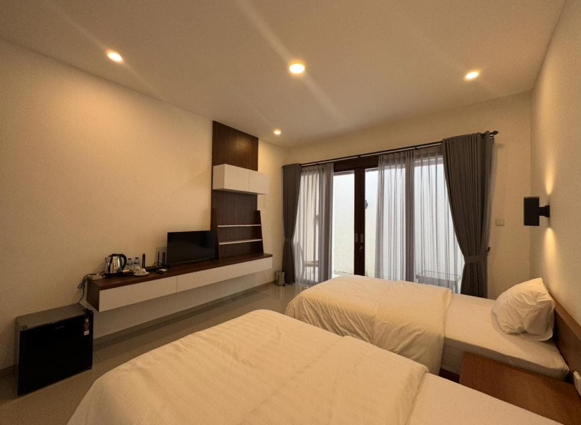 a hotel room with two beds and a television at Baruna Homestay Sanur in Sanur