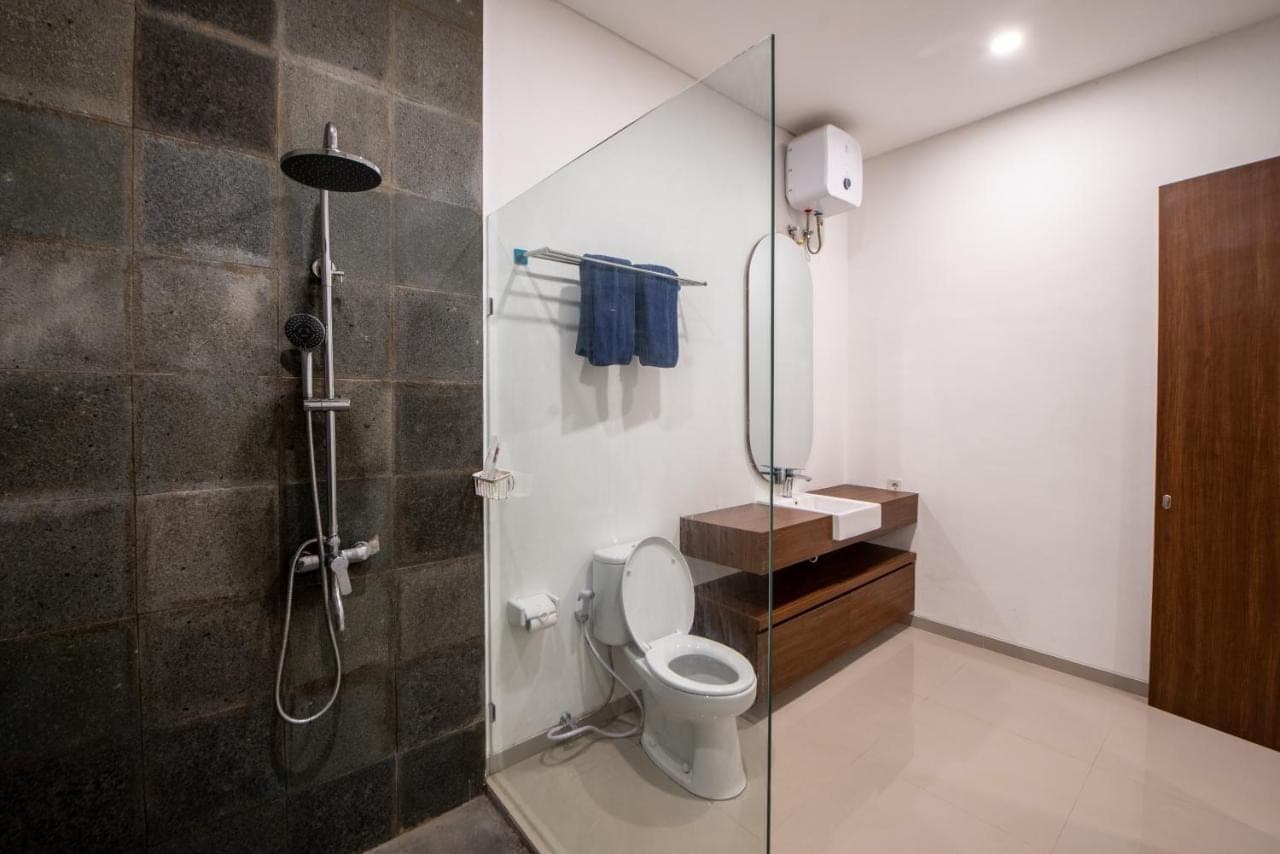 a bathroom with a shower with a toilet and a sink at Baruna Homestay Sanur in Sanur