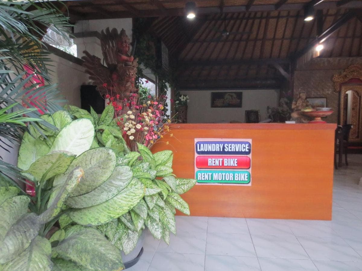 a counter with a sign that saysgency service next to plants at Putri Homestay in Sanur