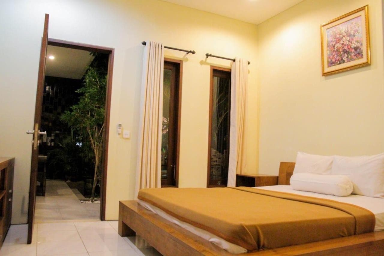 a bedroom with a bed and a sliding glass door at Putri Homestay in Sanur