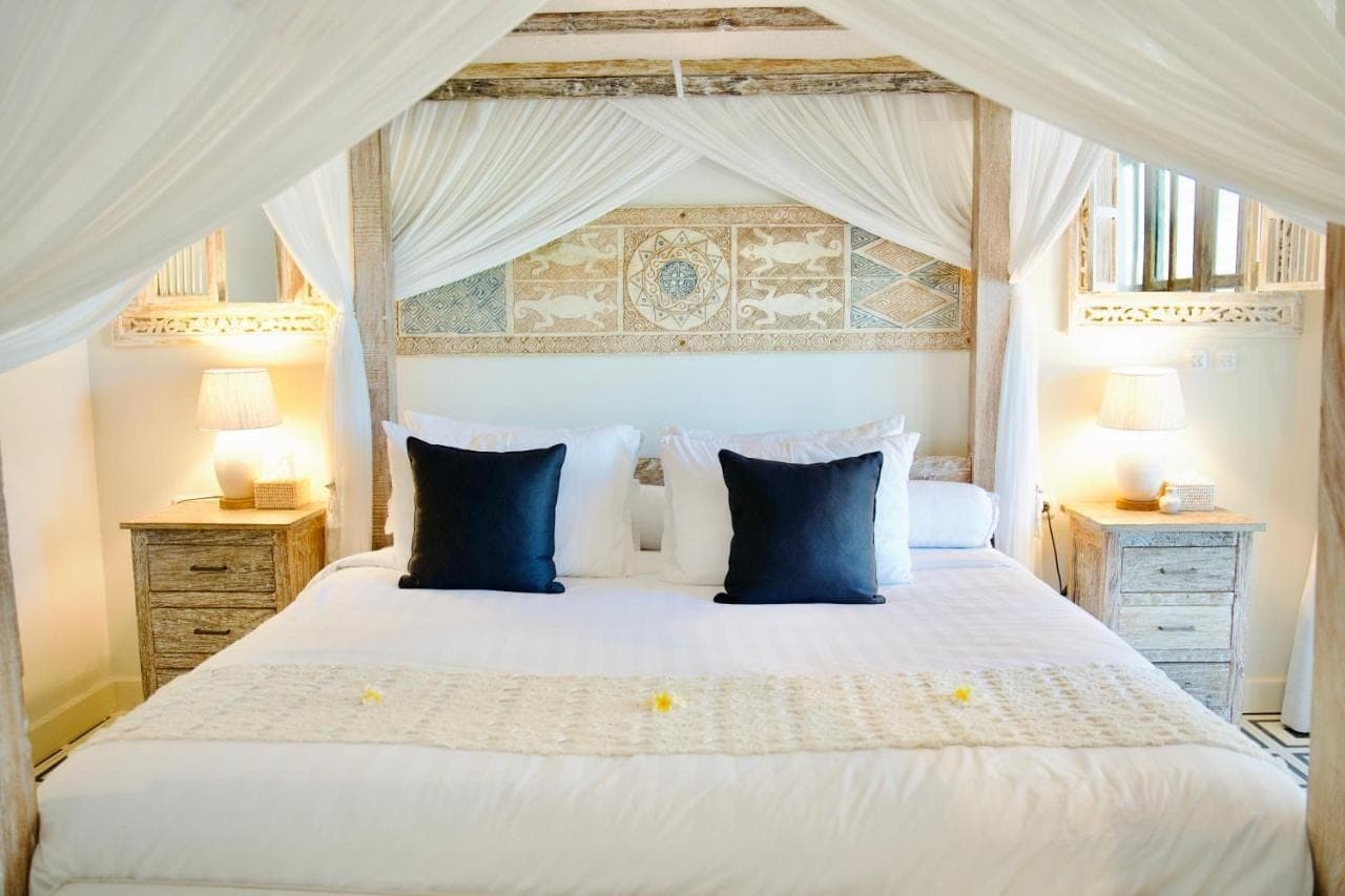 a bedroom with a large white bed with blue pillows at Dhauteya Villa in Amed