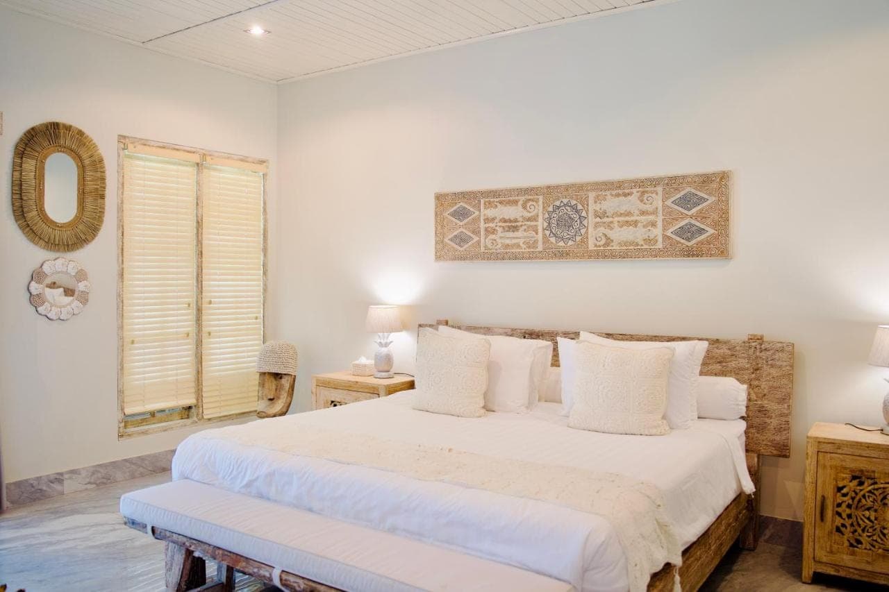 a white bedroom with a bed and a window at Dhauteya Villa in Amed