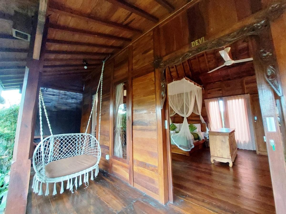 a room with a porch with a swing and a bed at Shivananda Antique Villas by EPS in Ubud