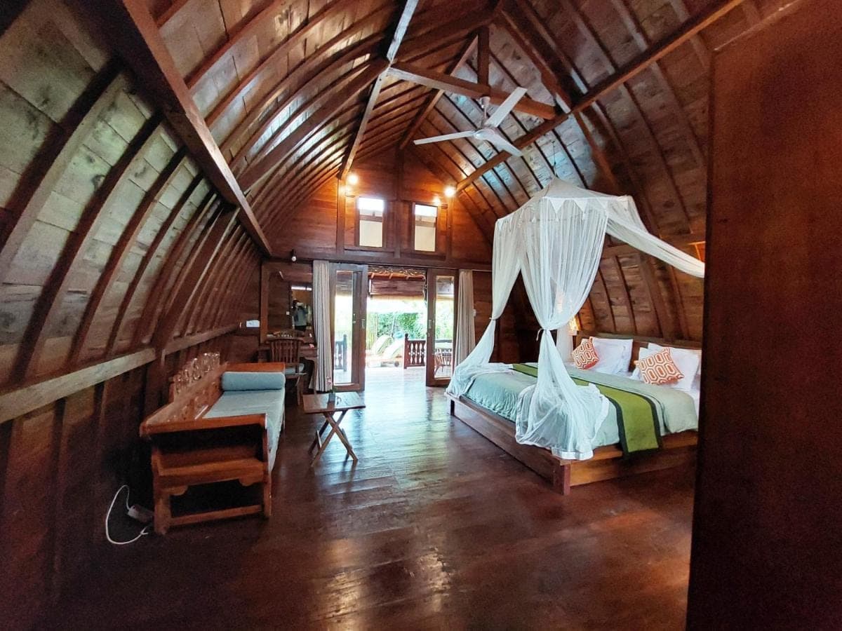 a bedroom with a bed in a wooden house at Shivananda Antique Villas by EPS in Ubud