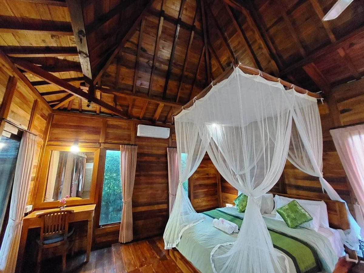 a bedroom with a canopy bed in a cabin at Shivananda Antique Villas by EPS in Ubud