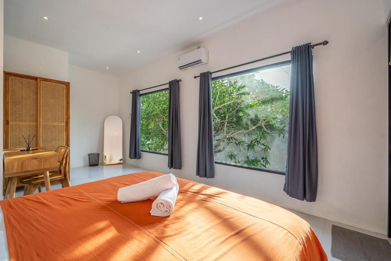 a bedroom with a bed and two windows and a desk at Nyma 2BR Villa Seminyak in Seminyak