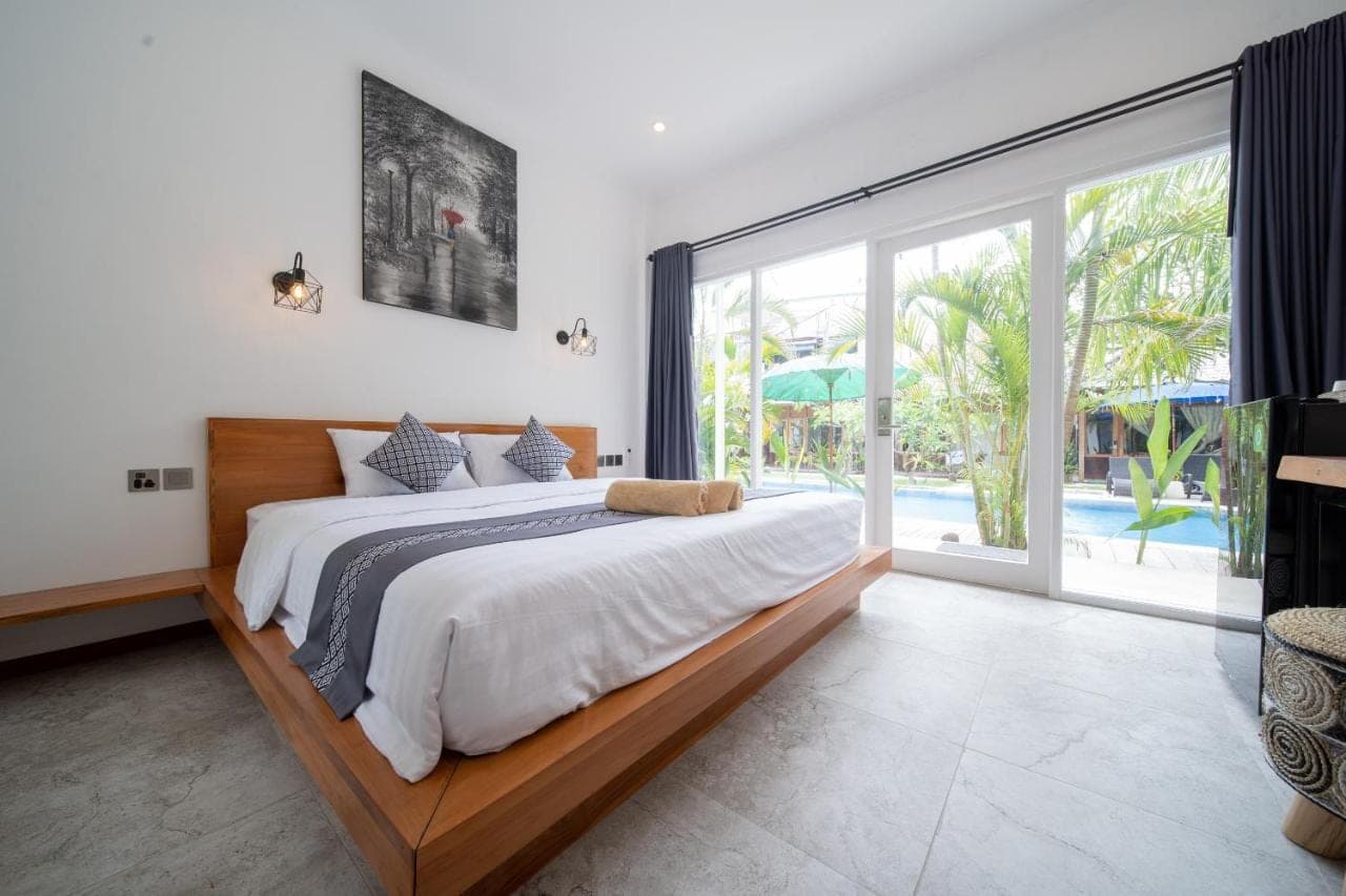 a bedroom with a large bed and a large window at Easy Surf Camp in Kuta