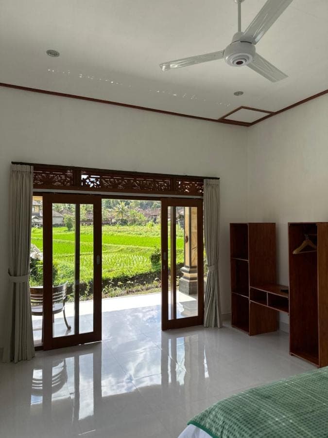 a bedroom with a bed and a sliding glass door at The babakan accommodations in Sidemen