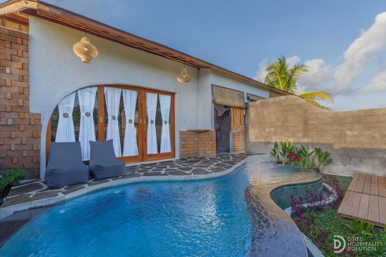 a villa with a swimming pool in front of a house at Lumina Villa Sidemen in Sidemen
