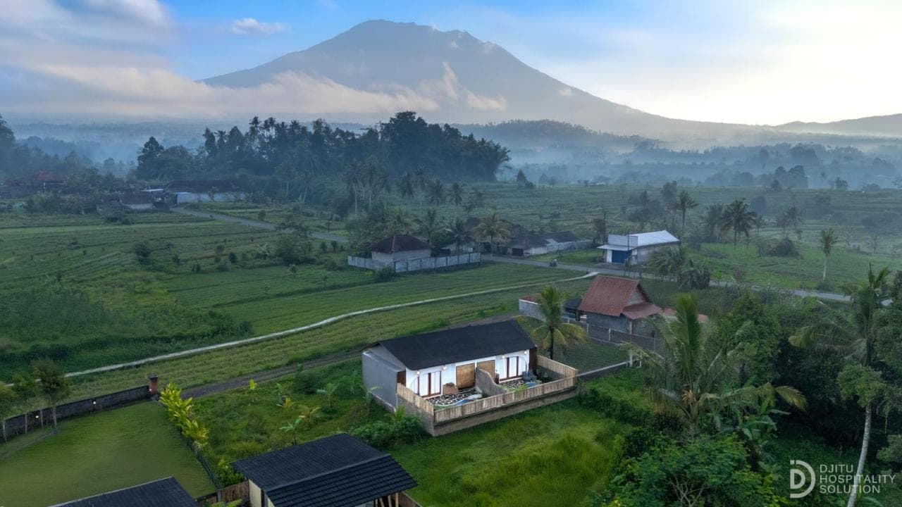 a house in a field with a mountain in the background at Lumina Villa Sidemen in Sidemen
