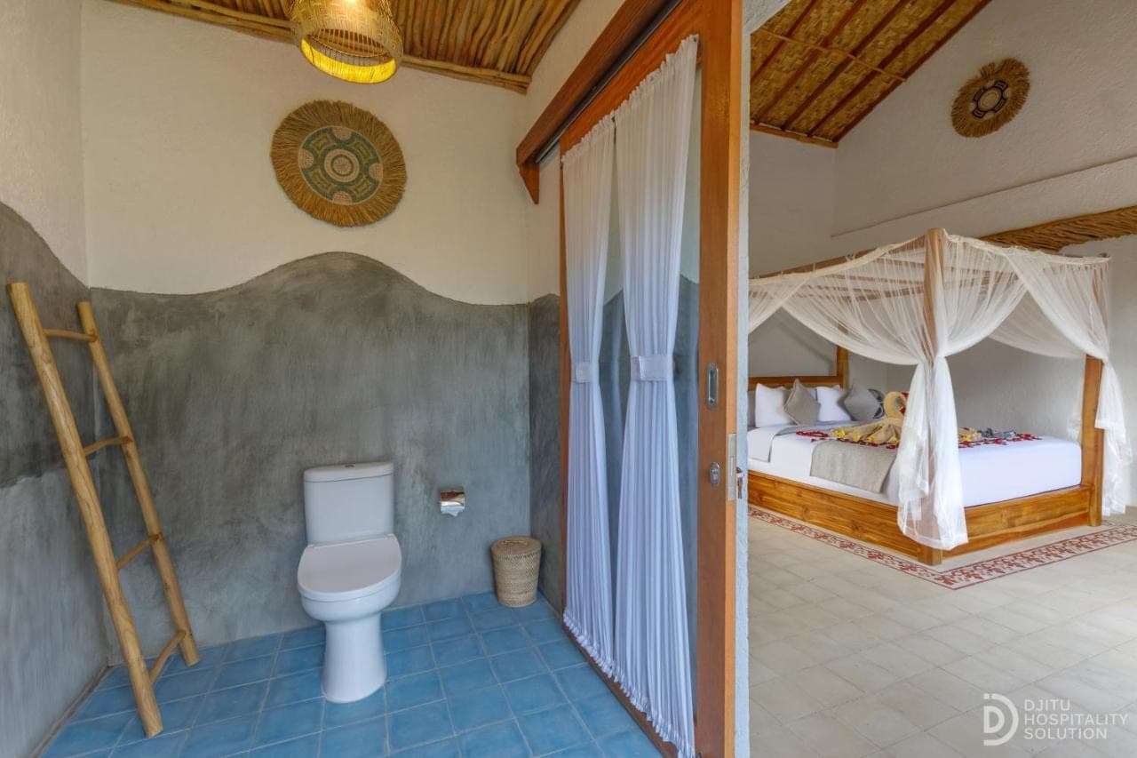 a bathroom with a toilet and a bed in a room at Lumina Villa Sidemen in Sidemen