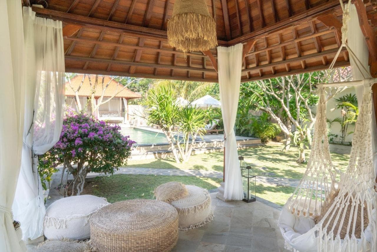a patio with hammocks and a yard with a pool at The Inn Possible in Uluwatu