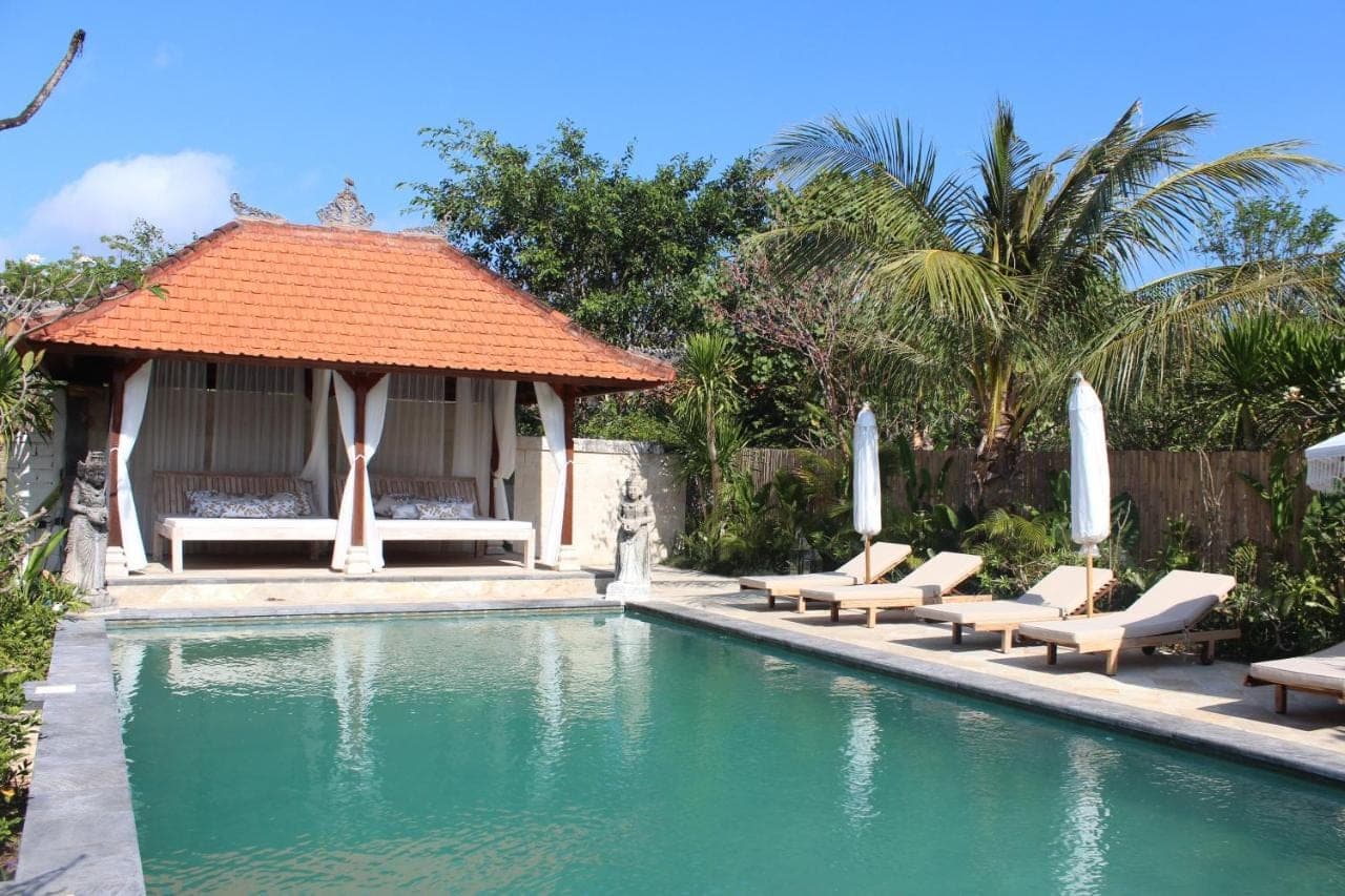a swimming pool with lounge chairs and a gazebo at The Inn Possible in Uluwatu