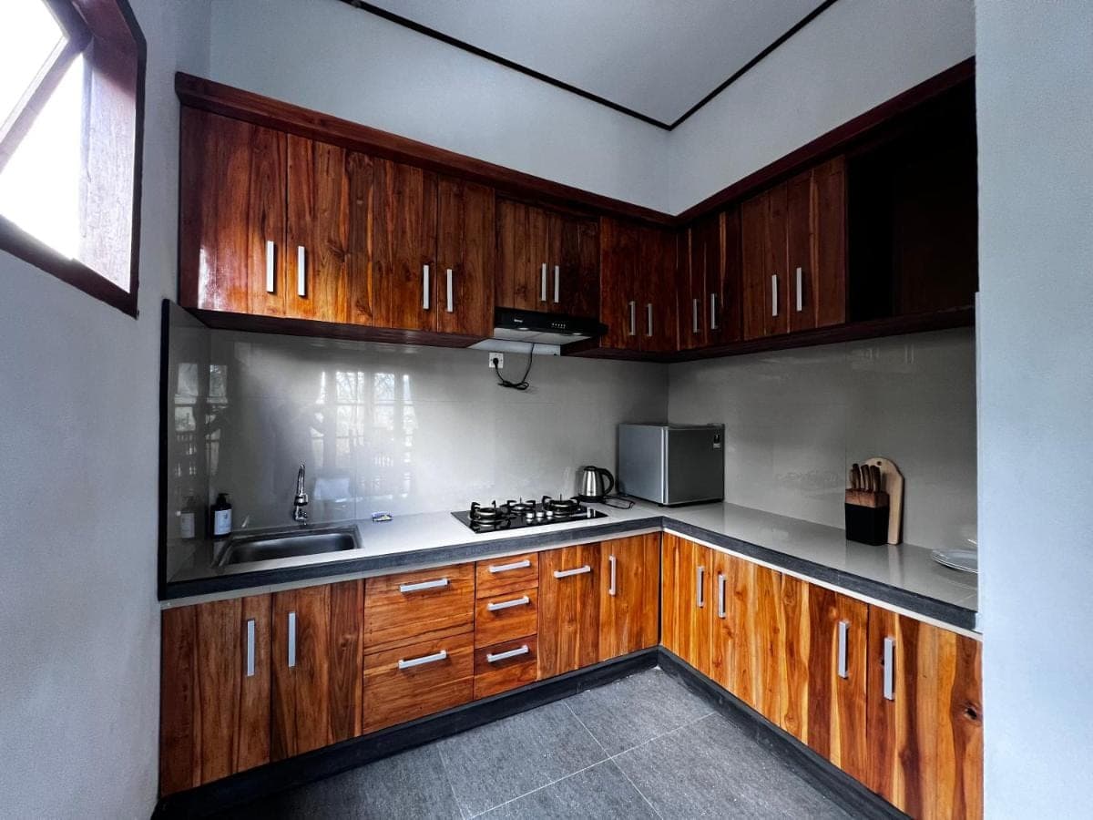 a kitchen with wooden cabinets and a stove top oven at Ume Dukuh Home Sidemen in Sidemen