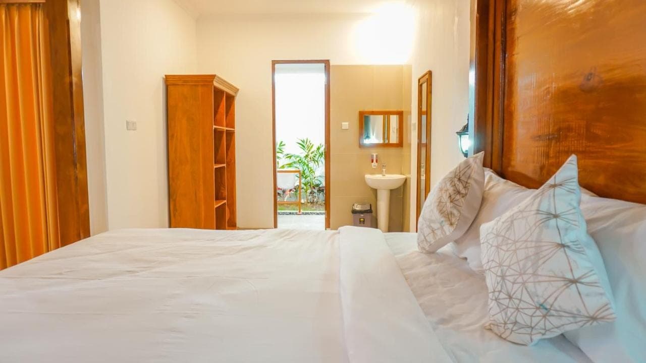 a bedroom with a white bed with a wooden headboard at Sunburn Villa in Nusa Dua
