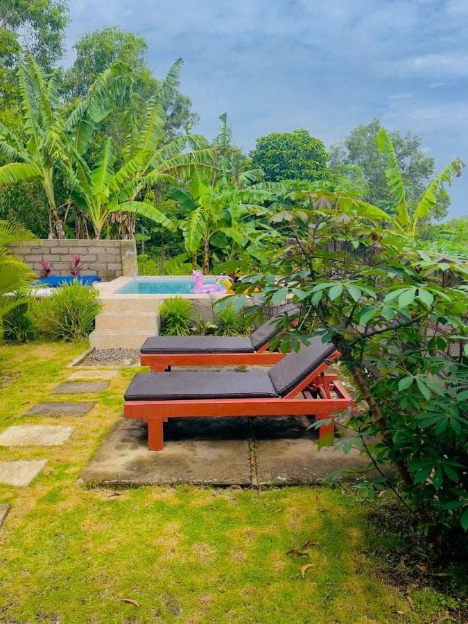 a group of benches sitting next to a pool at Sunburn Villa in Nusa Dua