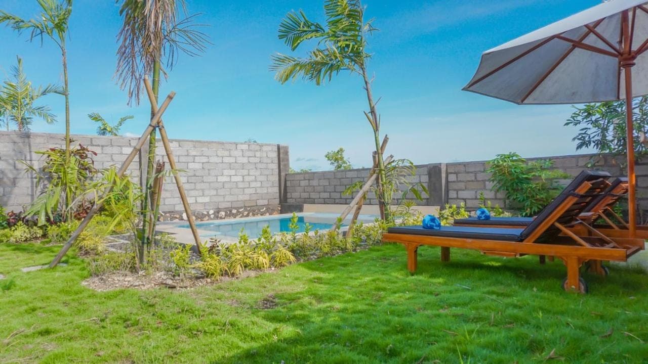 a hammock and an umbrella next to a pool at Sunburn Villa in Nusa Dua