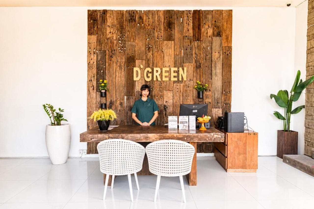 a man sitting at a wooden desk in a room at D'Green Nirava Kuta By Reccoma in Kuta