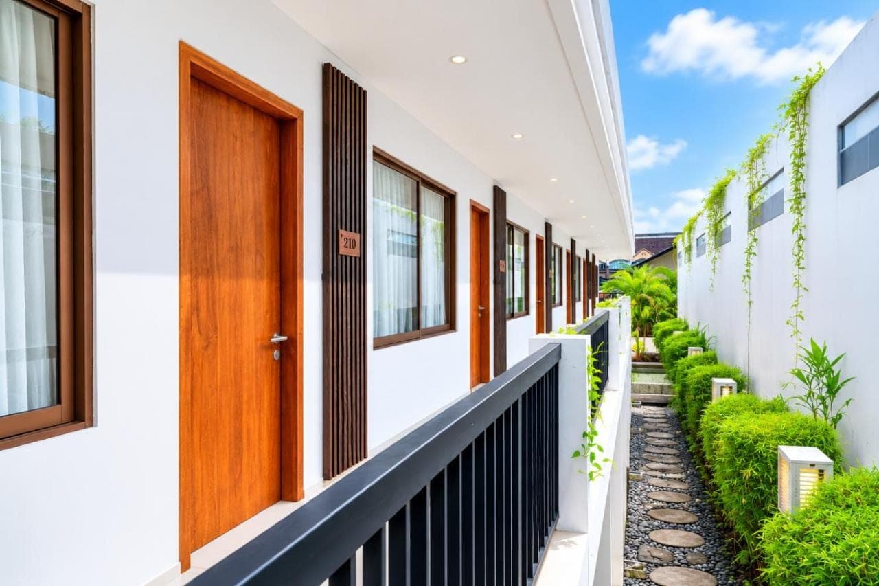 a row of white houses with a wooden door at D'Green Nirava Kuta By Reccoma in Kuta