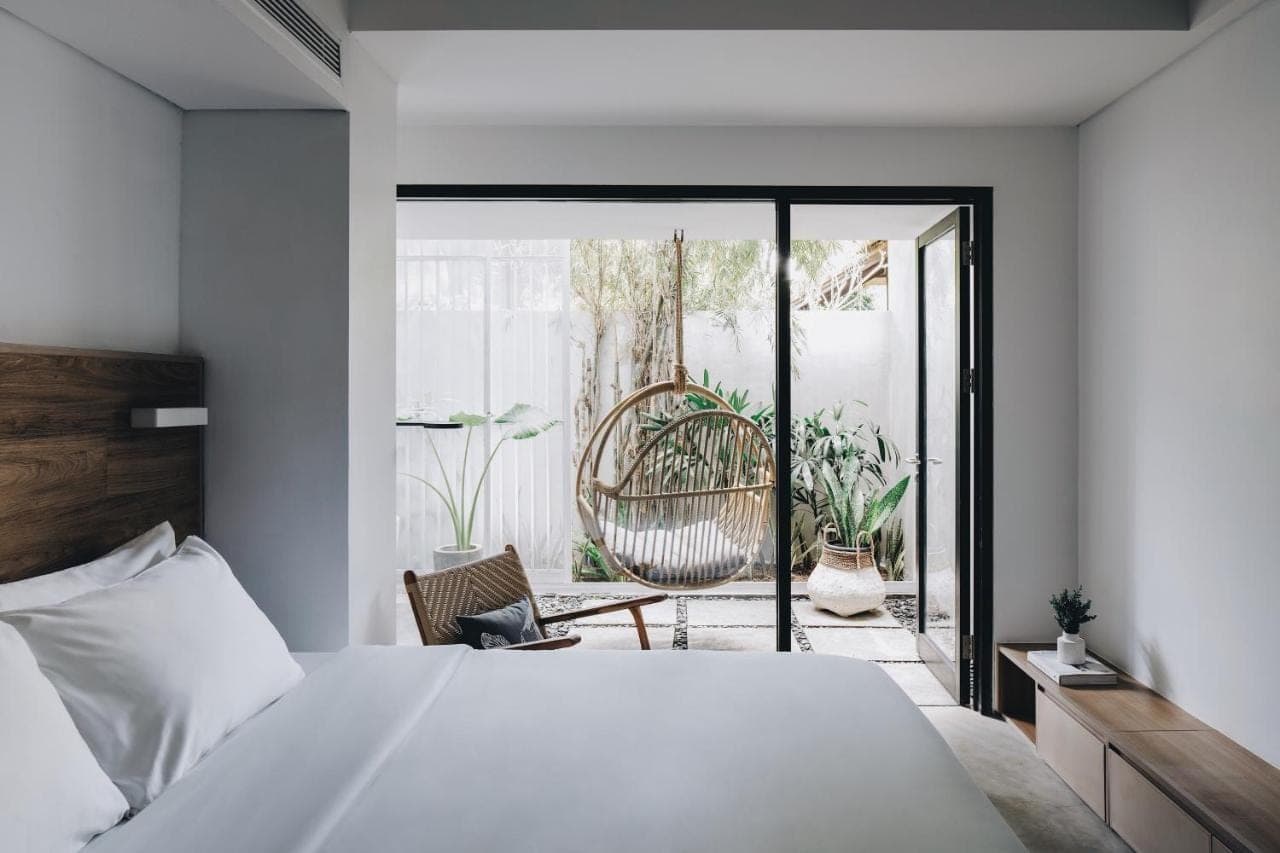 a bedroom with a large white bed and a patio at Lloyd's Inn Bali in Seminyak