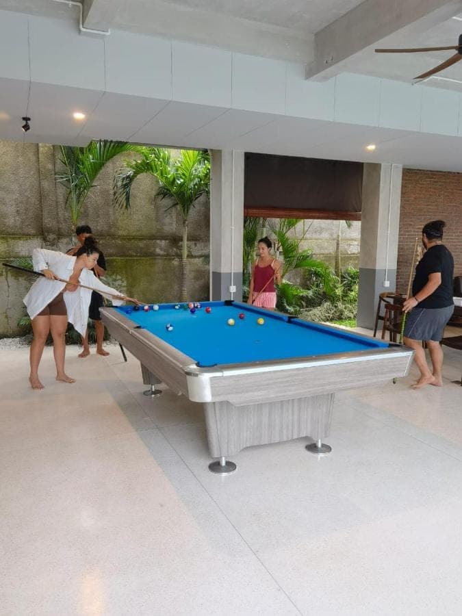 a group of people standing around a pool table at Nala's Home in Uluwatu