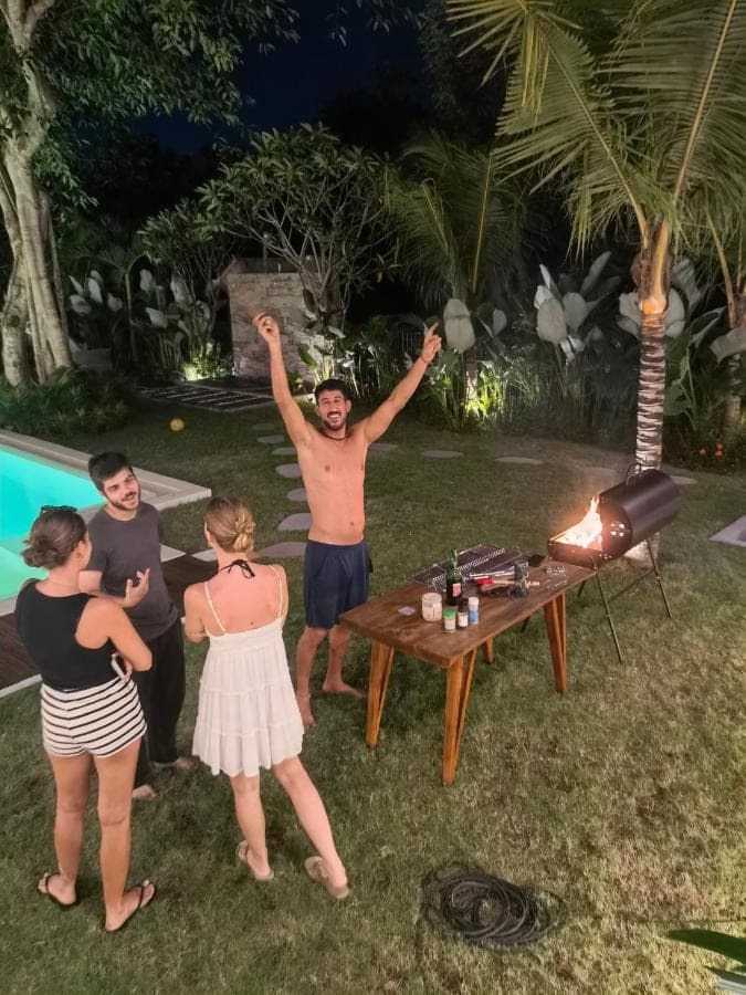 a group of people standing around a table with their hands in the air at Nala's Home in Uluwatu