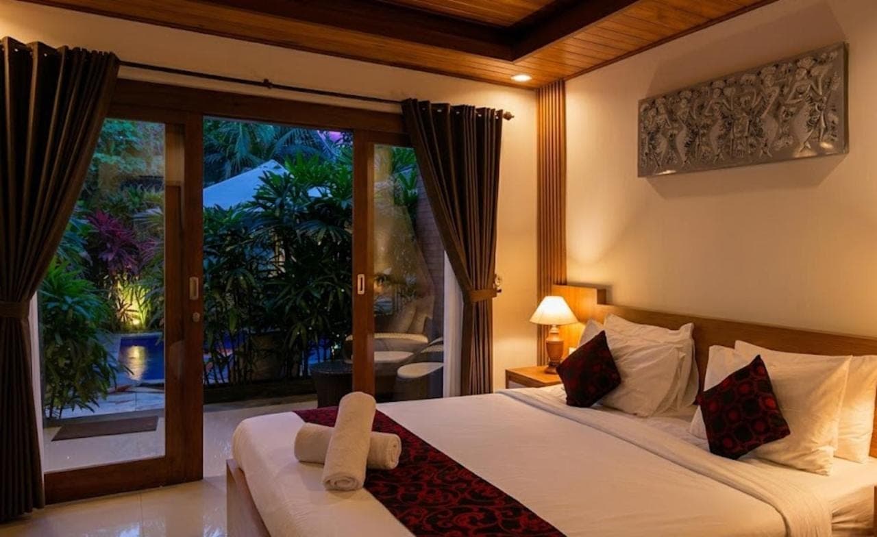 a bedroom with a large bed and a large window at Anindya Sanur in Sanur