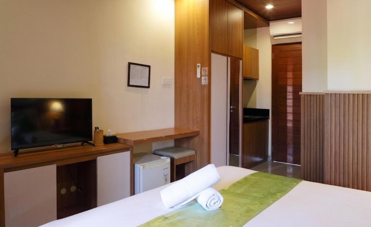 a bedroom with a bed and a tv and a desk at Anindya Sanur in Sanur