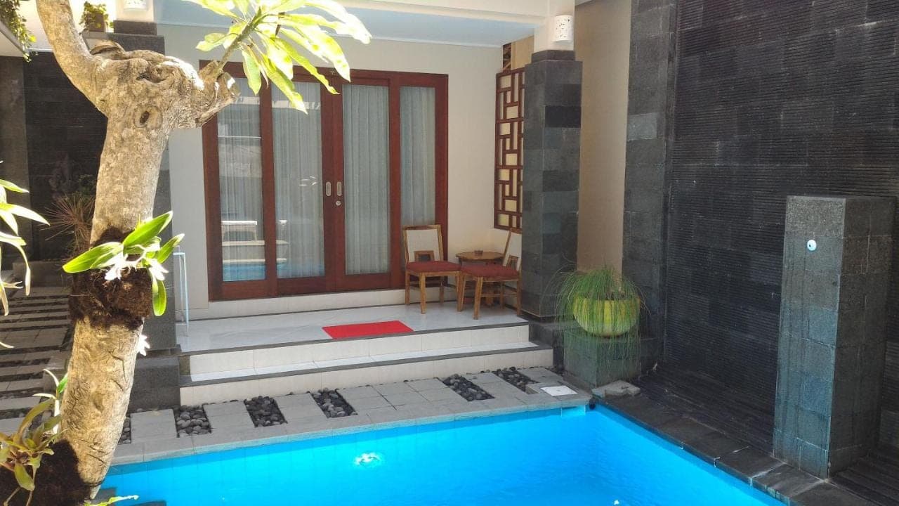 a villa with a swimming pool and a house at Nyaman Guest House in Sanur
